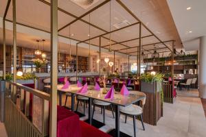 ein Restaurant mit Tischen und Stühlen, die mit rosa Servietten bedeckt sind in der Unterkunft VOYA Hotel in Ringsheim