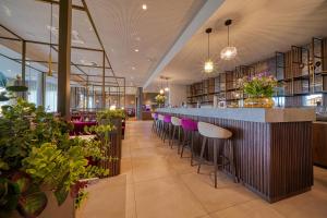 a library with a bar with purple stools at FourSide Hotel Ringsheim in Ringsheim