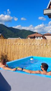 two men are sitting in a swimming pool at Apartman Gavro in Bajina Bašta