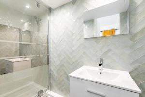 La salle de bains blanche est pourvue d'un lavabo et d'une douche. dans l'établissement Agréable appartement prés de Paris - II, aux Lilas