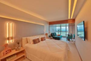 um quarto com uma grande cama branca e uma sala de estar em HY Apartments & Hotels no Recife