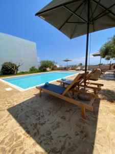 een zwembad met een parasol en twee stoelen en een tafel en een parasol bij Sirene Villas in Diakofti