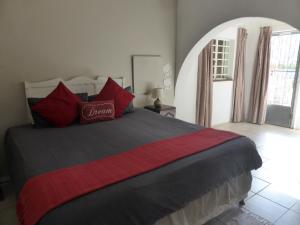 a bedroom with a large bed with red pillows at Orange Elephant Backpackers in Addo