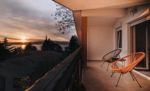 balcón con 2 sillas y vistas a la puesta de sol en Villa Pandora en Ohrid