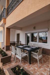 eine Terrasse mit einem schwarzen Tisch und weißen Stühlen in der Unterkunft Villa Pandora in Ohrid