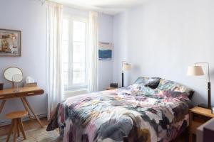 - une chambre avec un lit doté d'une couette colorée et d'une fenêtre dans l'établissement Spacious and central cocoon at the gates of Paris, à Levallois-Perret