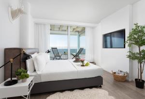 a white bedroom with a bed and a tv at Sea Executive Suites in Tel Aviv +75 photos