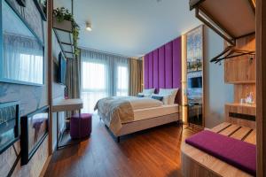 a bedroom with a bed and a purple wall at FourSide Hotel Ringsheim in Ringsheim