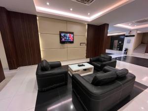 a living room with two black leather chairs and a tv at Raoum Inn Hafr Al Baten in Hafr Al-Batin