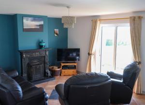 a living room with a couch chairs and a fireplace at Ballybunion Holiday Cottage No 10 in Ballybunion