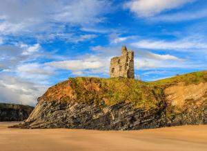 a castle on top of a cliff next to a beach at Ballybunion Holiday Cottage No 10 in Ballybunion