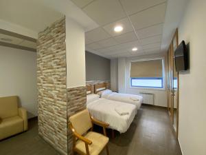 Habitación hospitalaria con 2 camas, sofá y TV en El Rinconcito de dpCristal, en Sarria