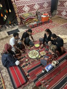 a group of people sitting around a table with pizza at Wadi Rum Desert Base Camp in Wadi Rum