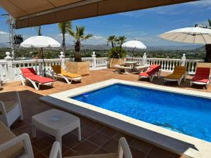 una piscina su una terrazza con sedie e ombrelloni di Casa Vista del Rey 77 ad Alhaurín el Grande