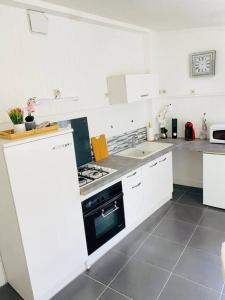 La cuisine est équipée de placards blancs et d'un four avec plaques de cuisson. dans l'établissement Maison vue sur mer, à Bretteville