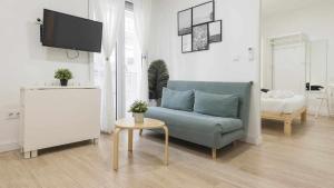 sala de estar con sofá azul y TV en Apartamentos Dimax by Toledo AP en Toledo