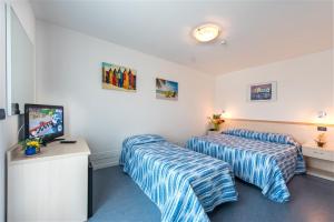 a hotel room with two beds and a flat screen tv at Hotel Minerva in Lignano Sabbiadoro