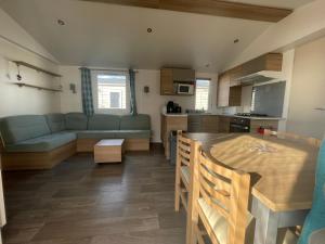 eine Küche und ein Wohnzimmer mit einem Tisch und einem Sofa in der Unterkunft Mobil home luxe 8 personnes avec wifi in Onzain