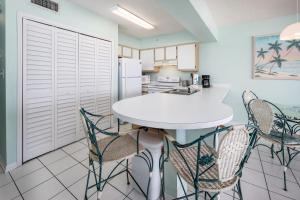 uma cozinha com uma mesa branca e cadeiras em Emerald Twrs West 2004 by Brooks and Shorey Resorts condo em Fort Walton Beach