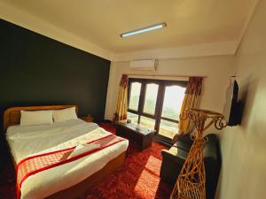 a bedroom with a bed and a large window at Hotell Hill Crown in Nagarkot
