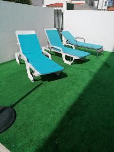 zwei blaue Liegestühle auf einem grünen Rasen in der Unterkunft Casinha Rés do Chão na Nazaré com Quintal e Barbecue in Nazaré