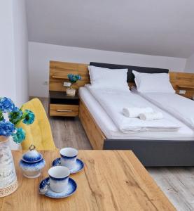 ein Schlafzimmer mit einem Bett mit zwei Tassen und einem Tisch in der Unterkunft ORI Blue Studio Malul Muresului in Arad