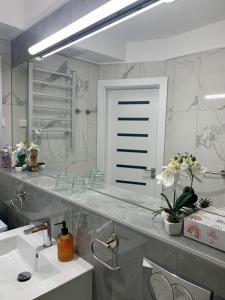 a bathroom with a sink and a large mirror at Spa Residence Carbona Hévíz Apartments KAKADU 203 B in Hévíz