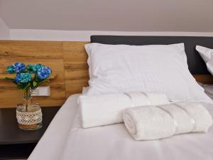 ein weißes Bett mit Handtüchern und eine Vase Blumen darauf in der Unterkunft ORI Blue Studio Malul Muresului in Arad