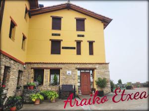 un edificio amarillo con puerta roja y ventanas en Araiko Etxea, 