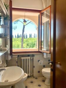 uma casa de banho com uma janela, um lavatório e um WC. em Villa dei Pini em Montopoli in Val dʼArno