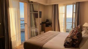 a bedroom with a bed and a balcony with the ocean at Hôtel Des Gouverneurs in Bastia