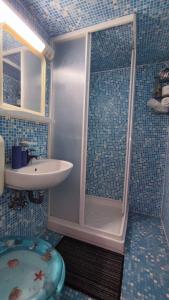 y baño de azulejos azules con ducha y lavamanos. en Királyos Pihenőház, en Háromhuta