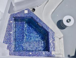 a swimming pool with blue tiles in a building at Aidos Villa Santorini in Megalokhori