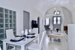 a white dining room with a white table and chairs at Aidos Villa Santorini in Megalokhori
