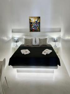 a white room with a bed with two towels on it at Aidos Villa Santorini in Megalochori