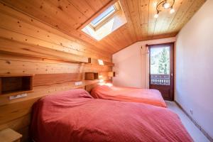 two beds in a room with wooden walls and a window at Apt Chénives 2 - Morzine in Morzine