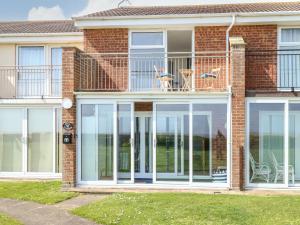 a house with large glass doors and a balcony at Gull Cottage in Lowestoft