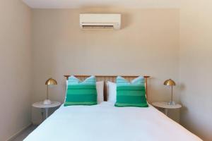1 dormitorio con 1 cama grande con almohadas verdes en Vine Close Apartment, en Healesville