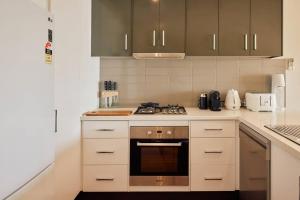 a kitchen with white cabinets and a stove top oven at Vine Close Apartment in Healesville