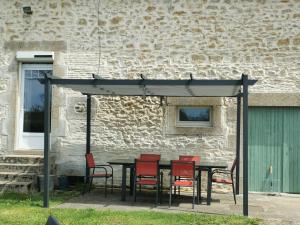 a table and chairs under a canopy in front of a building at La fermette des Étangs in Crux-la-Ville