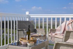 a table with a bottle of wine and glasses on a balcony at Bay View Lodge, Brynowen in Borth