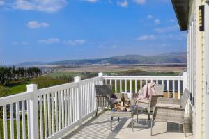 a balcony with chairs and a table with a view at Bay View Lodge, Brynowen in Borth