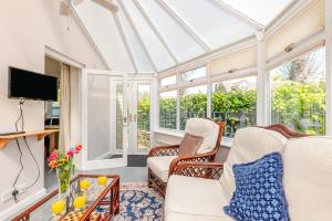 a conservatory living room with a glass ceiling at Elvington Cottage - Family-friendly cheerful house at the heart of the Cotswolds in Bourton on the Water