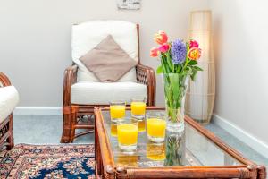 a glass coffee table with glasses of orange juice and flowers at Elvington Cottage - Family-friendly cheerful house at the heart of the Cotswolds in Bourton on the Water