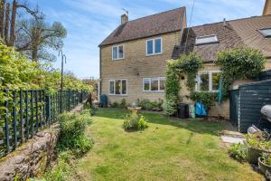 a house with a fence and a yard at Elvington Cottage - Family-friendly cheerful house at the heart of the Cotswolds in Bourton on the Water