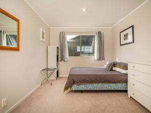 une chambre avec un lit, une commode et une fenêtre dans l'établissement Sandy Feet Retreat - Cooks Beach Holiday Home, à Cooks Beach