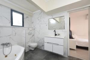 a white bathroom with a tub sink and a toilet at Levication 3 bedroom lakefront in Tiberias