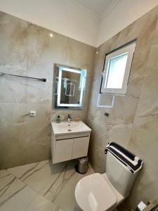 a bathroom with a toilet and a sink and a mirror at Oscar’s Apartments Drymades in Dhërmi
