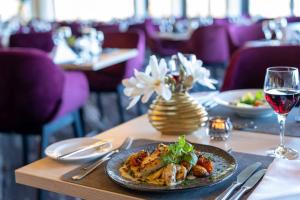 a table with a plate of food and a glass of wine at PLAZA Premium Timmendorfer Strand in Timmendorfer Strand
