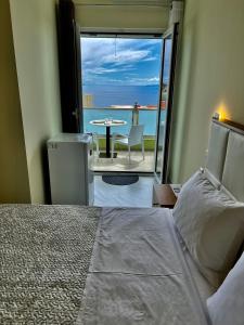 a bedroom with a bed and a view of the ocean at Oscar’s Apartments Drymades in Dhërmi